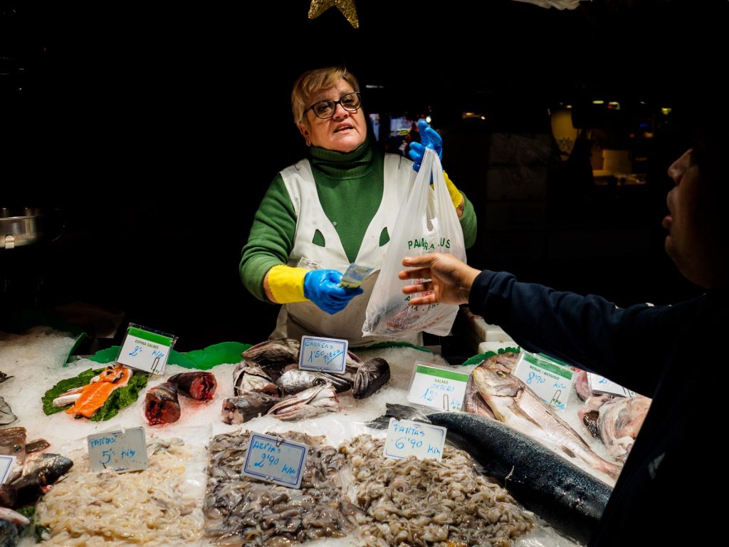A woman is selling fish in her post in La Boqueria, Barcelona